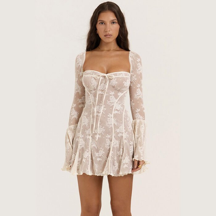 Woman wearing a sheer lace mini dress with flare sleeves and floral patterns