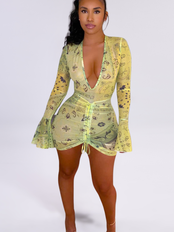 Model wearing a mint green paisley-printed ruched mini dress with a deep V-neckline and long bell sleeves.