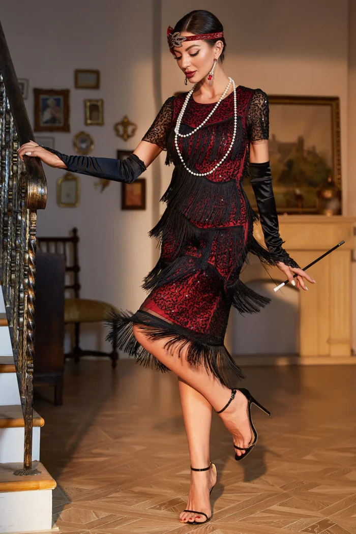 Woman wearing a vintage-inspired fringe and sequin midi dress in black-gold, standing in an elegant setting.
