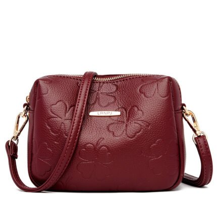 "Embossed clover crossbody bag in burgundy with adjustable strap." "Elegant emerald green embossed clover crossbody bag."