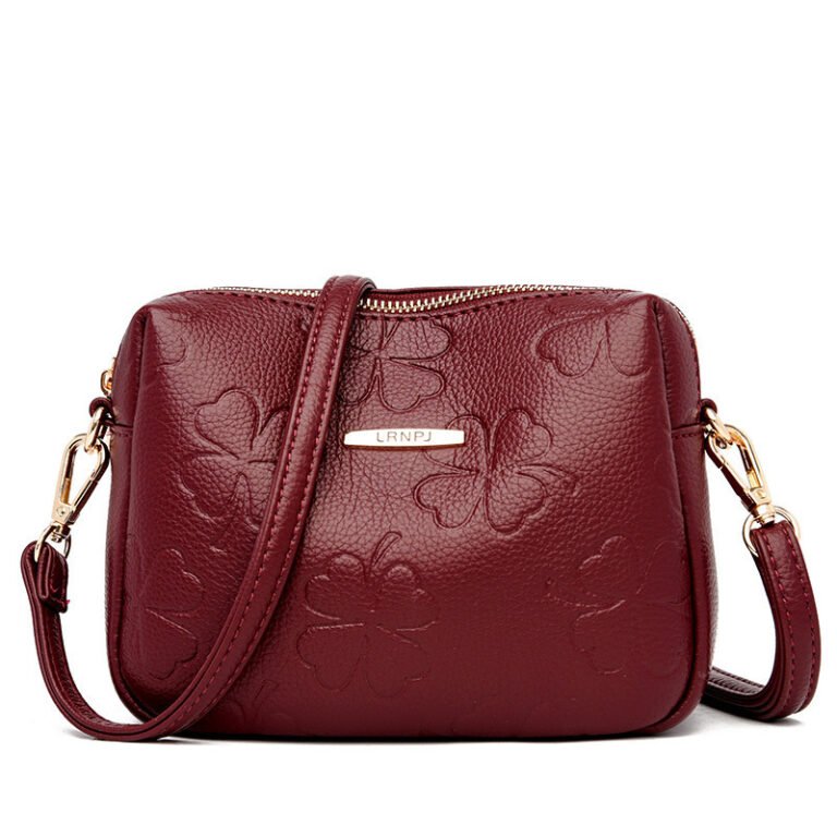 "Embossed clover crossbody bag in burgundy with adjustable strap." "Elegant emerald green embossed clover crossbody bag."