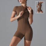 Model wearing a deep maroon zip-up active romper, showing a sculpted fit. Another model styled in a charcoal gray romper, posed for an athletic aesthetic.