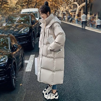 Model wearing a beige oversized puffer coat, styled with sneakers and jeans for a casual winter look. Two models wearing brown and blue puffer coats against a mountain backdrop.