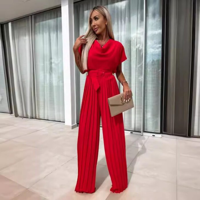 Model wearing a pleated wide-leg jumpsuit in red and black, styled with heels and a clutch.