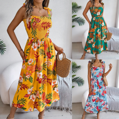 tropical floral smocked midi dress in yellow, teal, and sky blue, paired with a woven handbag.