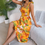 tropical floral smocked midi dress in yellow, teal, and sky blue, paired with a woven handbag.