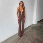 Woman wearing black cutout plunge halter jumpsuit in studio