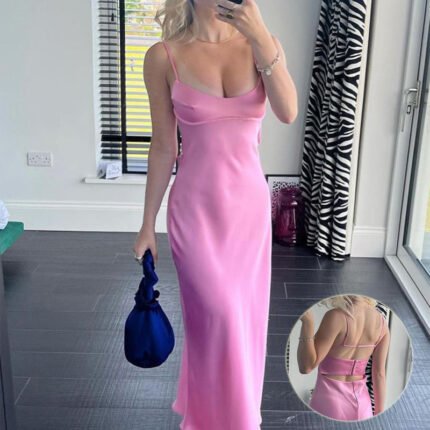 Woman wearing pink satin slip dress with open back and spaghetti straps Front view of pink satin maxi dress with cowl neckline Elegant pink open-back dress styled for summer indoors