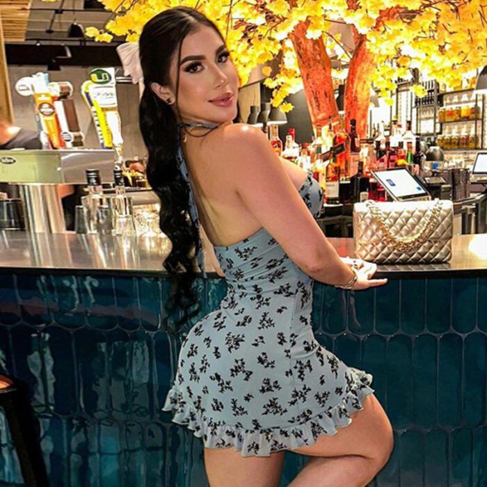 Model wearing floral mini dress with ruffle hem in a chic indoor and outdoor setting.