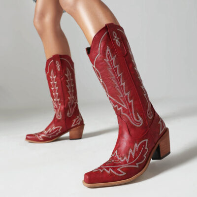 Image Alt: Close-up of red Western cowboy boots with white stitching and block heels