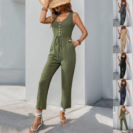 Woman wearing olive sleeveless cropped jumpsuit with back view Woman wearing beige cropped sleeveless jumpsuit holding a woven bag Woman in black utility jumpsuit styled with strappy sandals