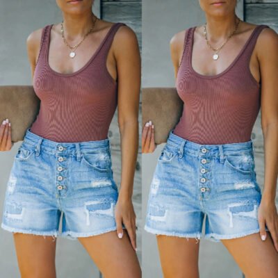Model wearing high-rise distressed denim shorts with tank top