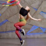 Model wearing high-waisted gradient mesh print leggings in pink, yellow, and blue ombré effect