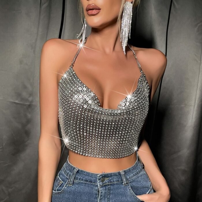 Woman wearing a silver rhinestone crop top with cowl neckline and chain halter straps.