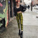 Models wearing plaid high-waisted pants in black and white checkered, red plaid, and yellow tartan prints, paired with white sneakers.