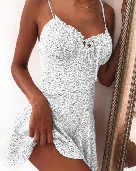Woman wearing a white floral mini dress with sweetheart neckline and tie-front detail.