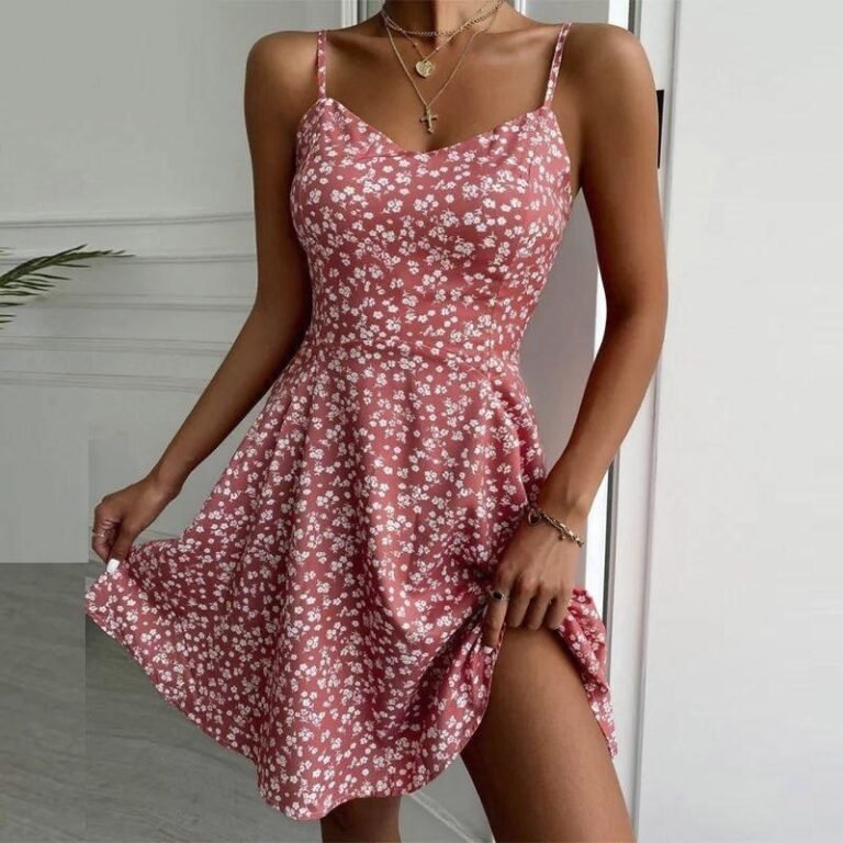 Woman wearing a blush pink spaghetti strap mini dress with white floral print.
