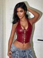 Woman wearing deep red faux leather halter corset top with lace-up front, styled with jeans and body chain.