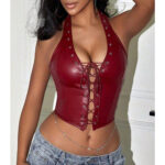 Woman wearing deep red faux leather halter corset top with lace-up front, styled with jeans and body chain.