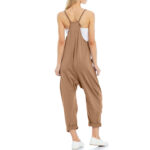 Relaxed fit sleeveless jumpsuit with pockets in neutral tones, styled with sneakers for casual wear.