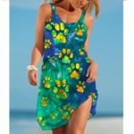 Woman wearing a sleeveless pet print beach slip dress with a scoop neckline, relaxed fit, and side slit, shown in multiple paw print, shell, bone, and dog-inspired designs.