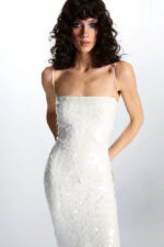 Light-colored fitted midi dress with tonal paillette embellishment and spaghetti straps.