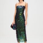 Close-up of oversized green, blue and black reflective paillettes across dark fabric.
