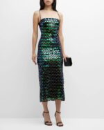 Close-up of oversized green, blue and black reflective paillettes across dark fabric.